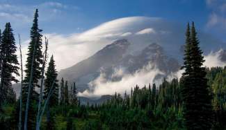 Door de wolken lijkt het niet of Mount Rainier een Helm op heeft.